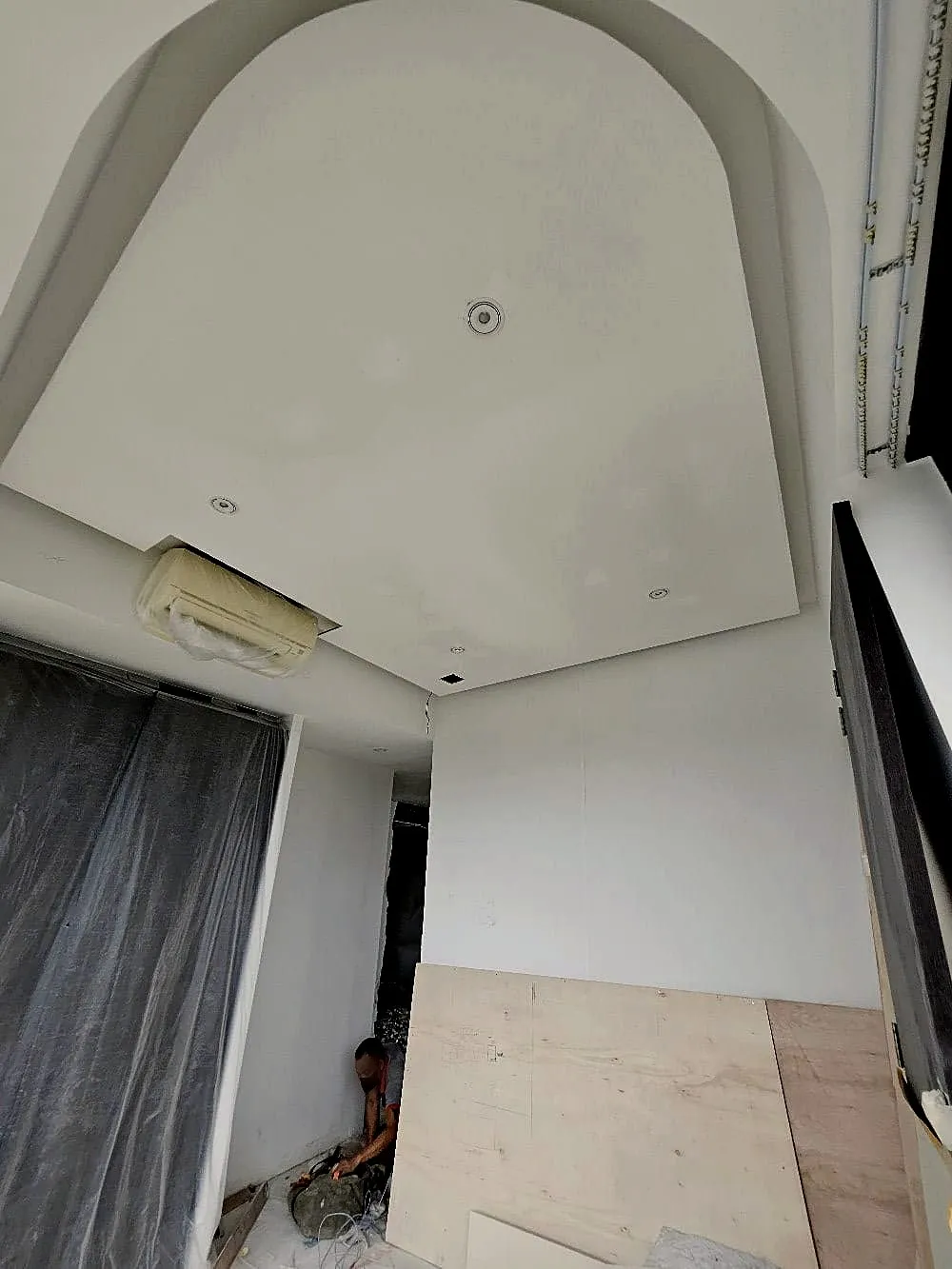 An arched false-ceiling bulkhead plastered and sanded ready for paint, with the air-conditioning unit wrapped and the floor boarded over