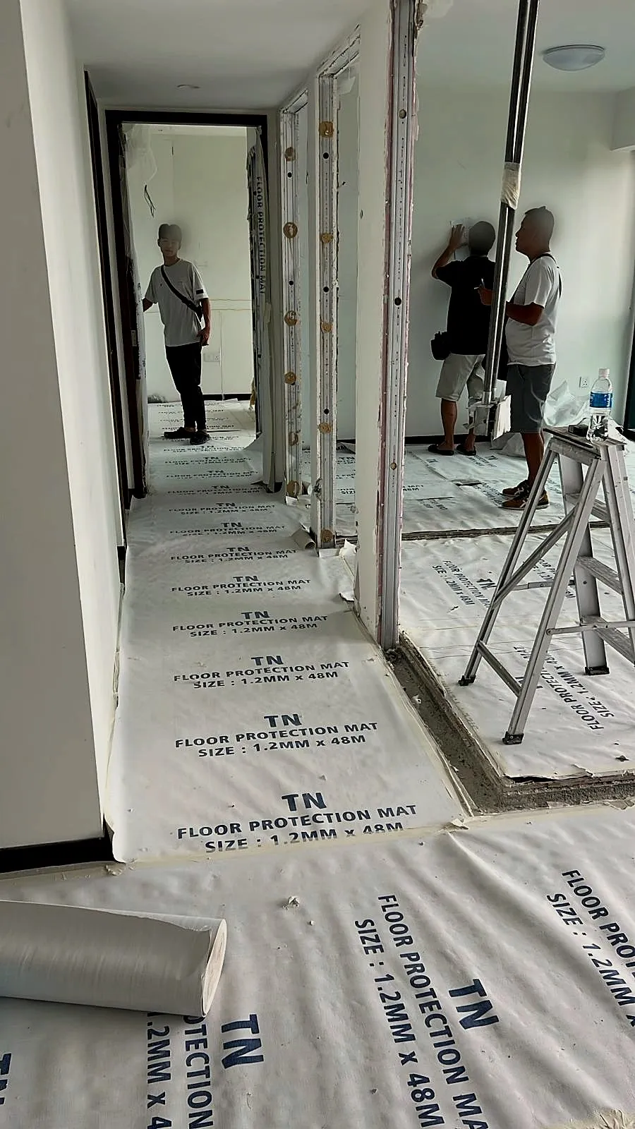 Protection matting rolled wall to wall along a corridor and into two rooms while the crew works on the walls