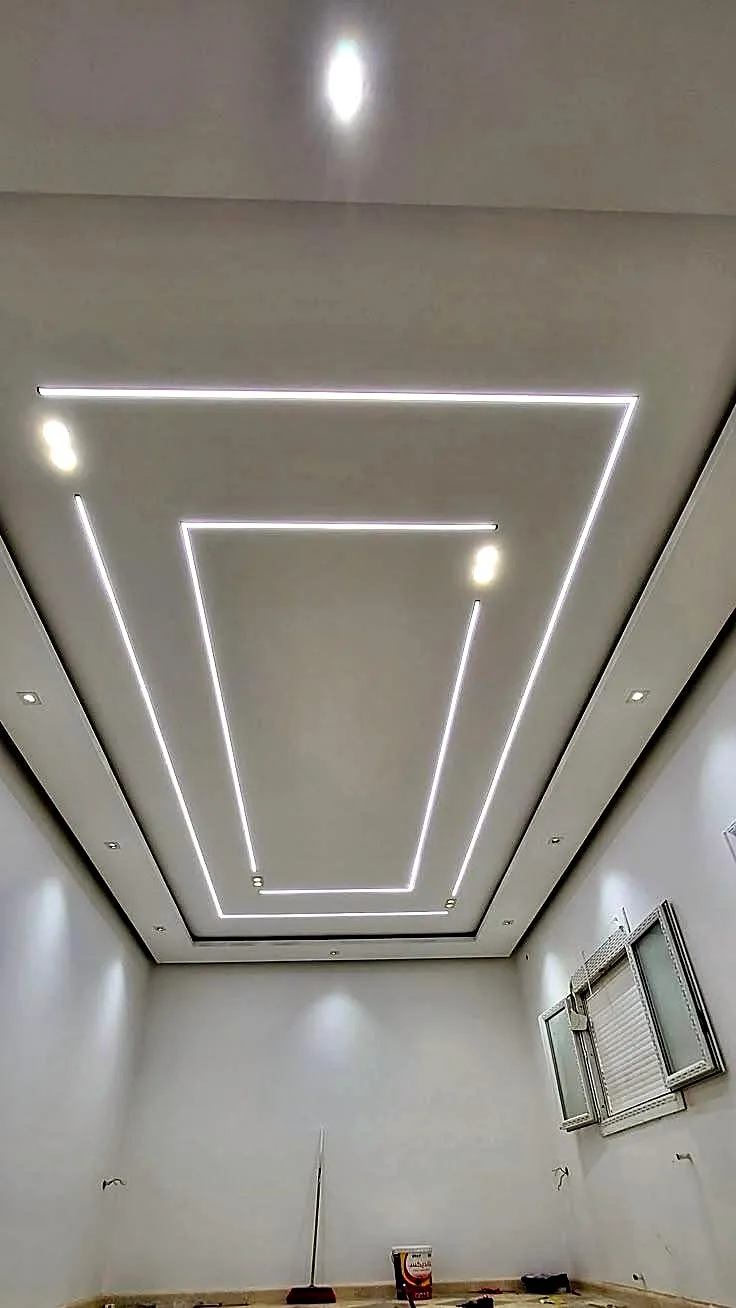 A recessed ceiling with concentric linear LED channels running around a stepped bulkhead