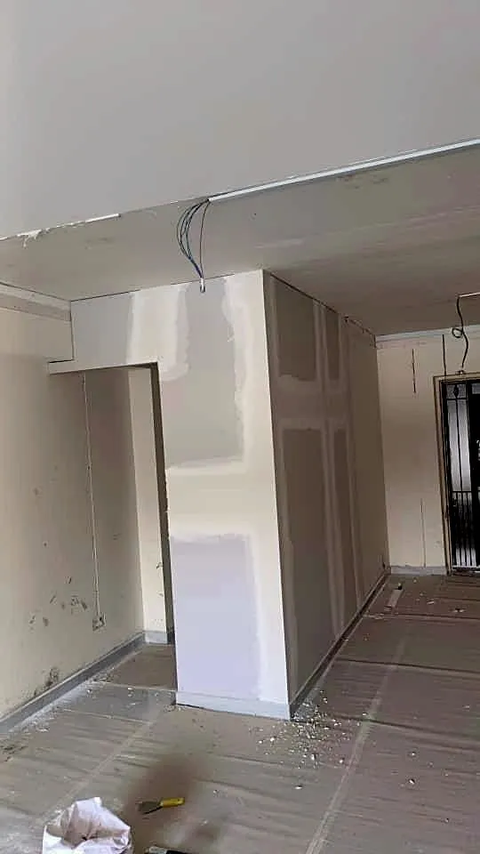 A newly built partition and bulkhead skim-coated ready for paint, with the ceiling wiring left tailed out